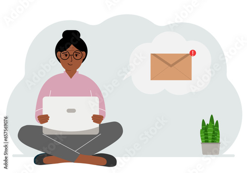 A woman sits cross-legged working with a laptop and opens an email. The concept of education, work, correspondence.