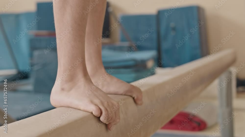 Low section of Biracial little girl walking on balance beam during indoor gymnastic training in class Low section of Biracial little girl walking on balance beam during indoor gymnastic training in class