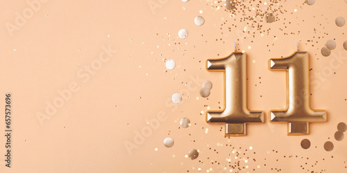 Gold candles in the form of number eleven on peach background with confetti. 11 years celebration. photo