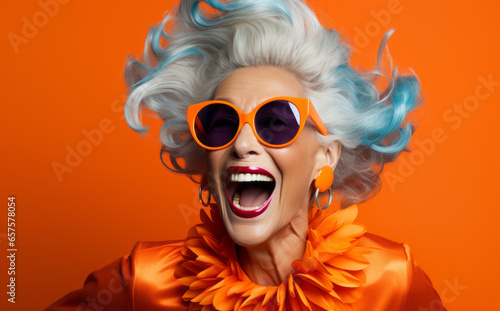 Old lady Surprised and excited, opening eyes and mouth in outrageous party clothing and bright sunglasses, Bright solid orange and purple color background