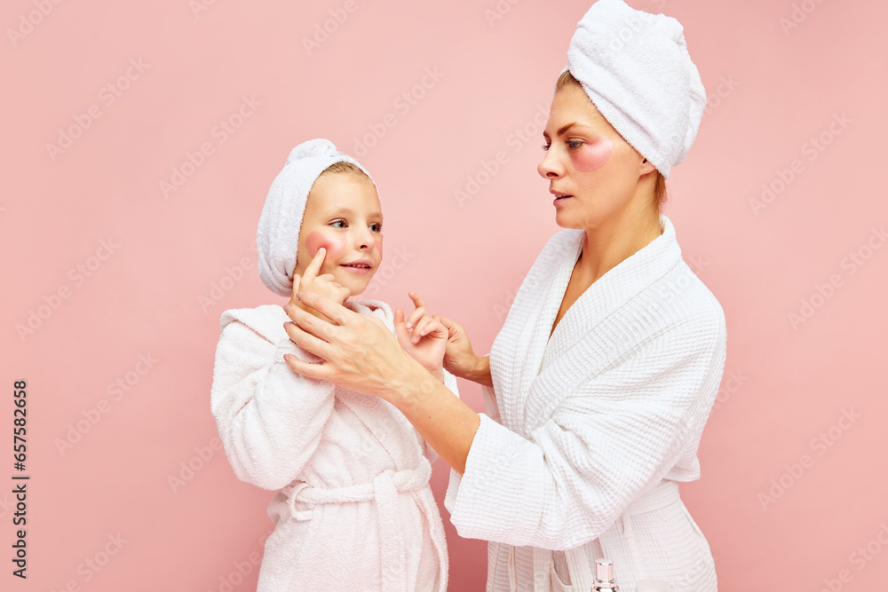 Home spa. Loving mother and daughter in bathrobes and towels using beauty product for skincare, eye patches. Women and child together care of beauty. Home spa. Loving mother and daughter in bathrobes and towels using beauty product for skincare, eye patches. Women and child together care of beauty.