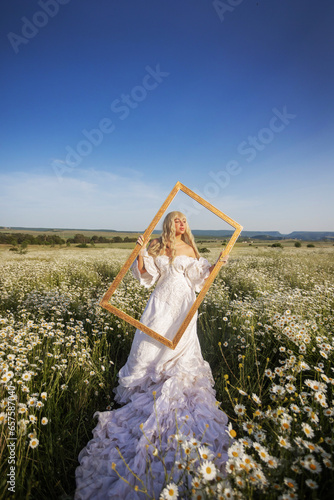 Girl in a white dress and a crown with a bouquet in a chamomile field at sunset, view from the back, a princess on a walk photo