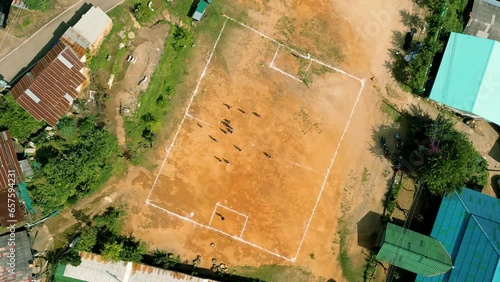 4K Cinematic sport aerial drone footage of children playing on a footbal field in the mountain village of Doi Pui next to Chiang Mai, Thailand on a sunny day