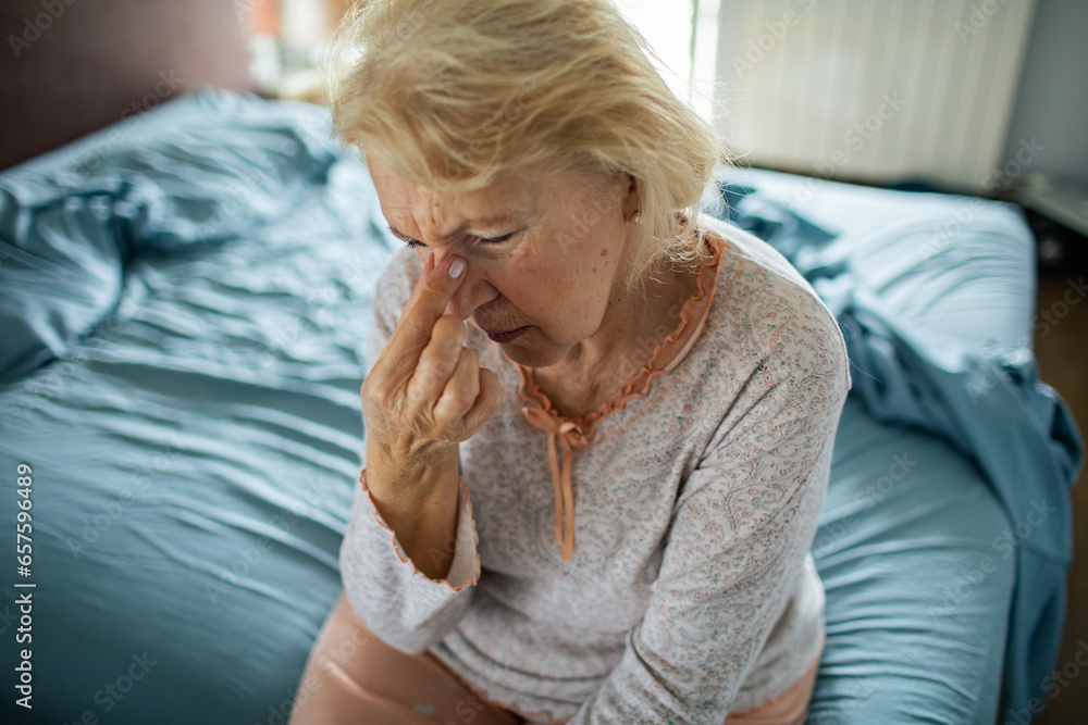 Stressed senior woman sitting on her bed at home Stressed senior woman sitting on her bed at home