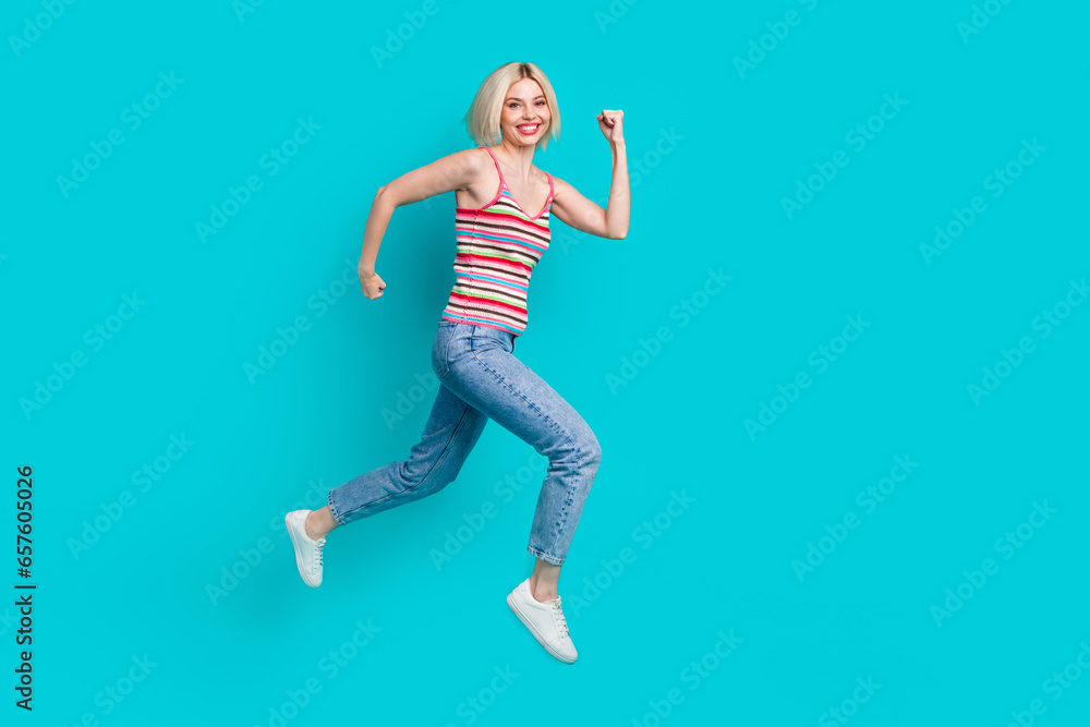 Full length photo of cute excited lady wear striped singlet jumping high empty space isolated turquoise color background Full length photo of cute excited lady wear striped singlet jumping high empty space isolated turquoise color background