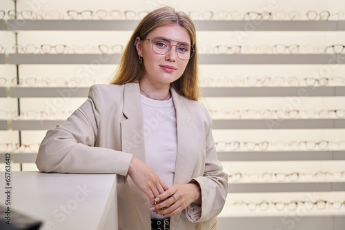 Beautiful young woman in glasses stands at the counter