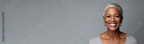 Banner Beautiful elegant mature grey haired middle aged african American woman with perfect skin and smile , on grey background, copyspace for text photo
