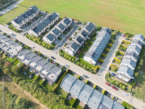 Aerial view of residential houses neighborhood and apartment building complex at sunset. Tightly packed homes  driveway surrounds green tree flyove. Suburban housing development