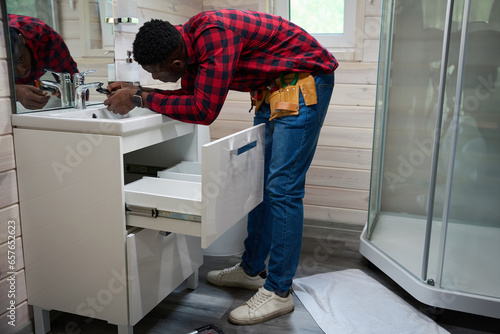 Male worker makes minor repairs in the bathroom photo