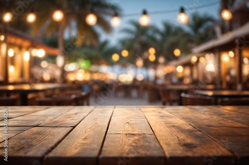Empty wooden table with blur beach cafes background and bokeh lights