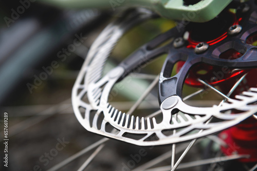 Close-up of Hydraulic bicycle disc brakes, gray metal disc attached to a bicycle wheel close-up, effective popular mountain bike brakes. Bicycle spokes on a gray background