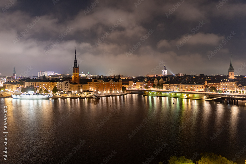Stockholm, Sweden: city lights and night view of Stadsholmen district (Gamla Stan) and Riddarholmen district, buildings reflected in the water. Cityscape with illumination, Riddarfjarden marina