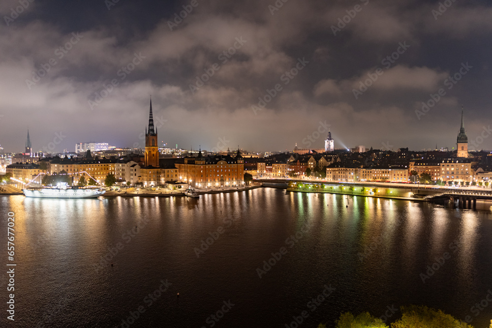 Obraz premium Stockholm, Sweden: city lights and night view of Stadsholmen district (Gamla Stan) and Riddarholmen district, buildings reflected in the water. Cityscape with illumination, Riddarfjarden marina