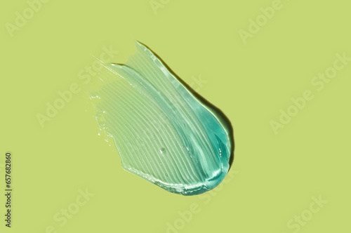 Liquid blue cosmetic gel or vaseline smudge texture on green lime background