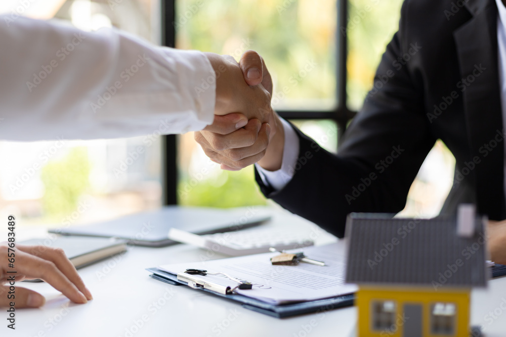 Businessman shaking hands with real estate agent in office after reaching home purchase agreement.