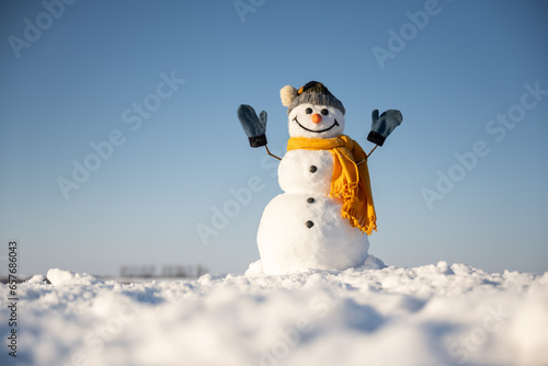 Snowman with hands up on snowy field. Winter holidays concept