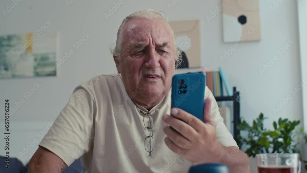 Medium shot of sad senior man having problems when using modern smartphone at home Medium shot of sad senior man having problems when using modern smartphone at home