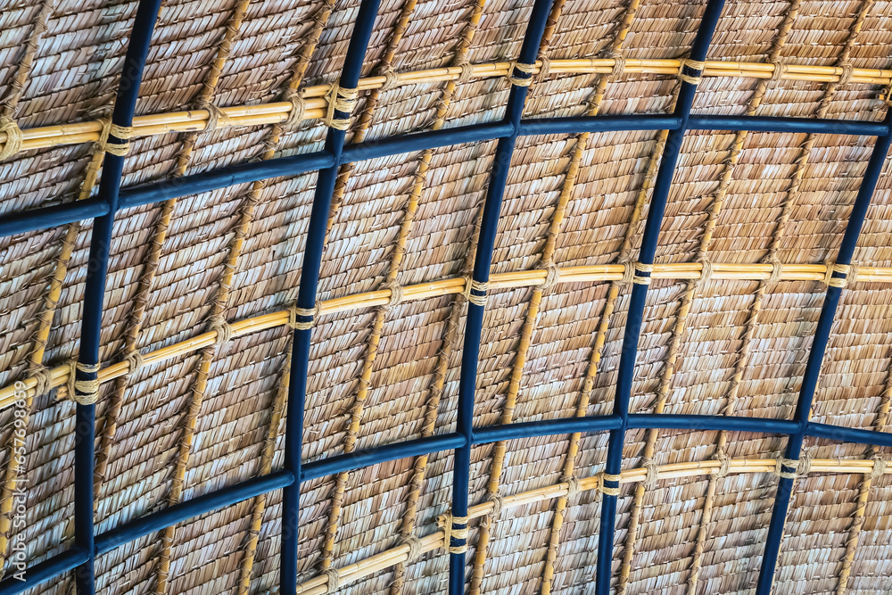 Beautiful thatched roof surface detail of mixed materials pattern structure by weave pile straw with steel bars. .Roof​ made​ of​ straw. Pattern of under bamboo roof frame..Wooden thatched ceiling.