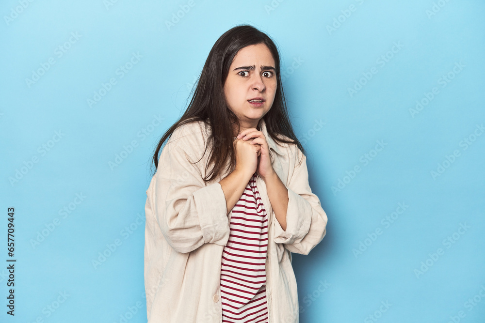 Young Caucasian woman on blue backdrop scared and afraid. Young Caucasian woman on blue backdrop scared and afraid.