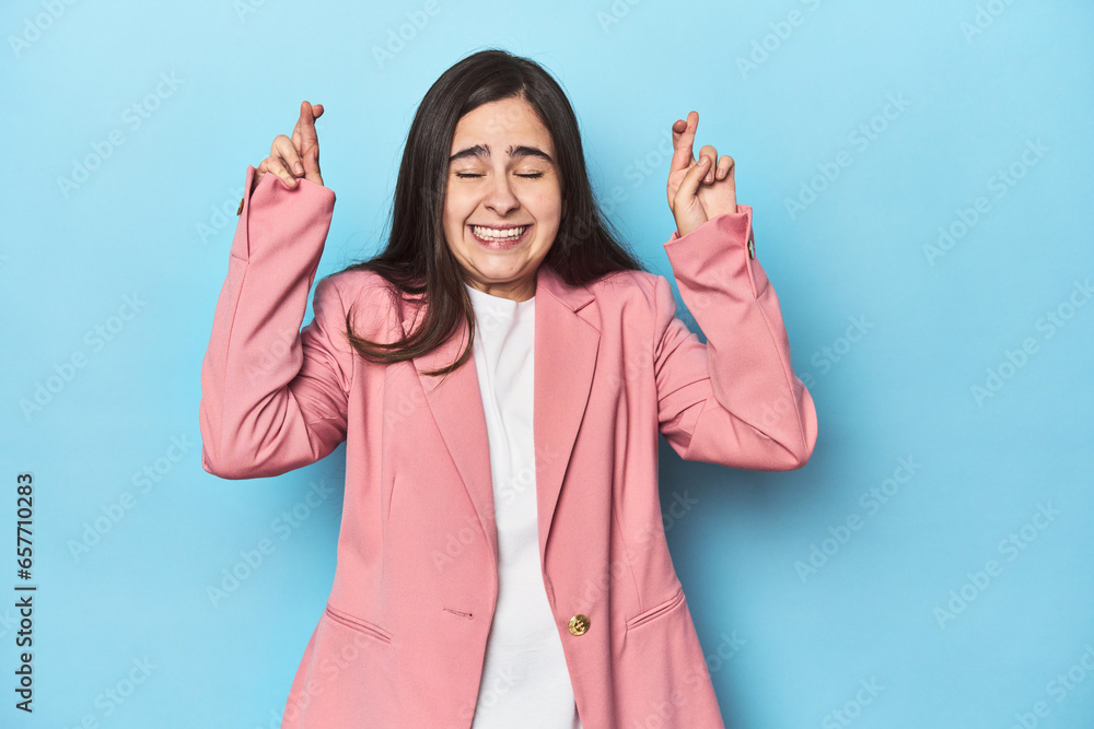 Young Caucasian woman on blue backdrop crossing fingers for having luck Young Caucasian woman on blue backdrop crossing fingers for having luck