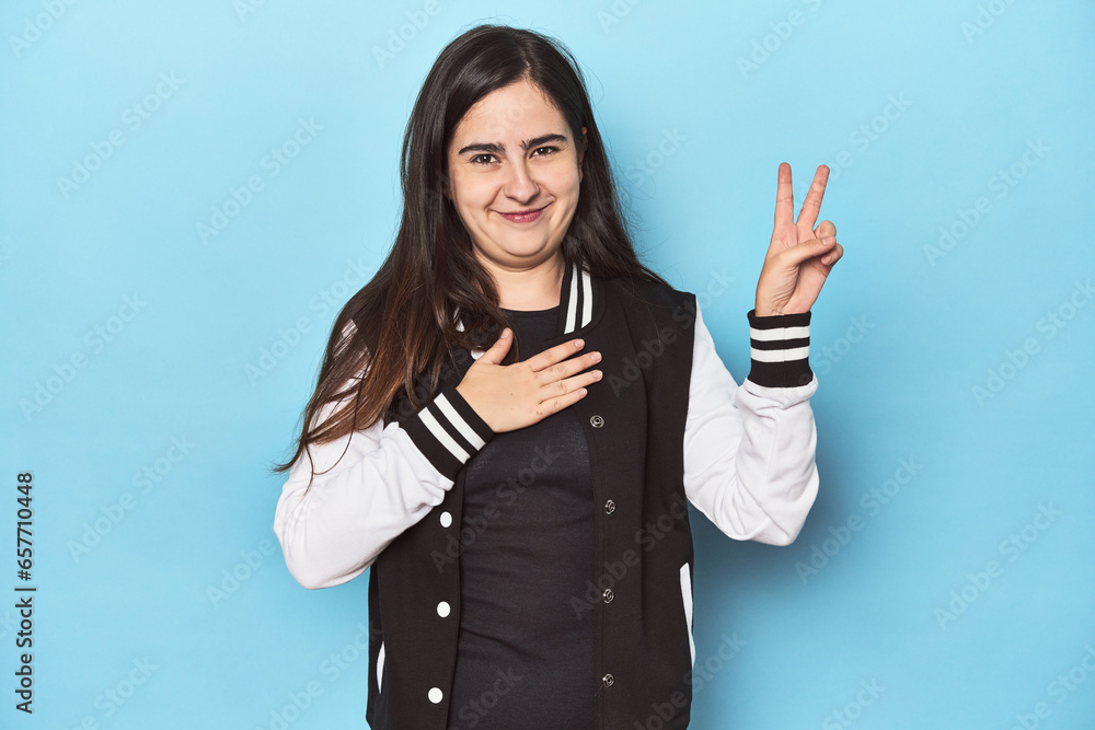 Young Caucasian woman on blue backdrop taking an oath, putting hand on chest.