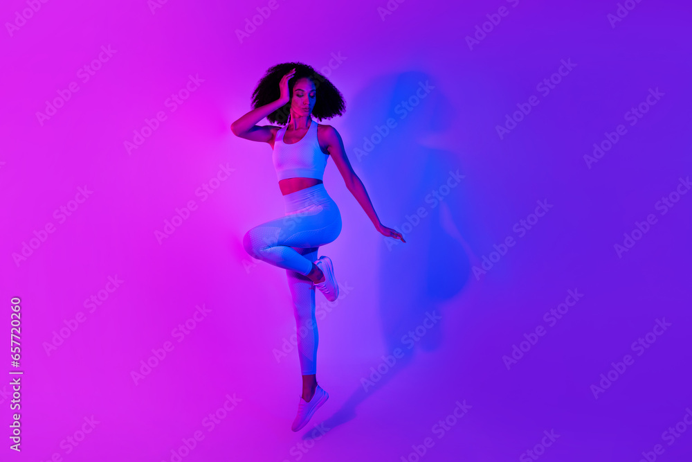 Full length portrait of sportive beautiful person jumping empty space advert isolated on pink blue color neon background Full length portrait of sportive beautiful person jumping empty space advert isolated on pink blue color neon background