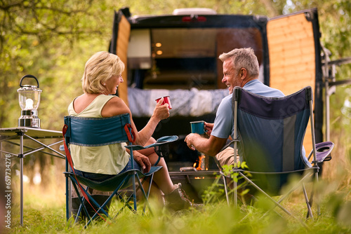 Fotografie Rear View Of Senior Couple Camping In Countryside With RV Drinking Coffee By Out
