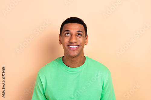 Photo portrait of attractive young man look interested up empty space wear trendy green clothes isolated on beige color background