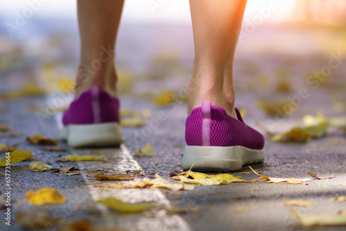 Women feet in violet shoes on autumn leaves. Feet, shoes, nature walk. Selective focus