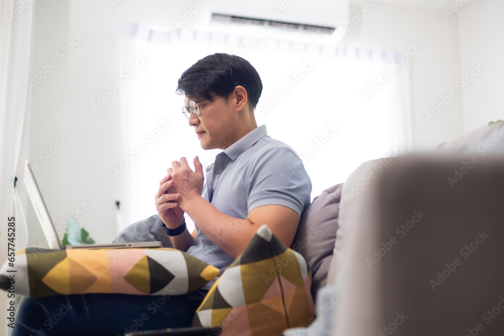 Office syndrome. Asian thai businessman suffering from shoulders neck and back pain after working long time at home office workplace - obrazy, fototapety, plakaty 