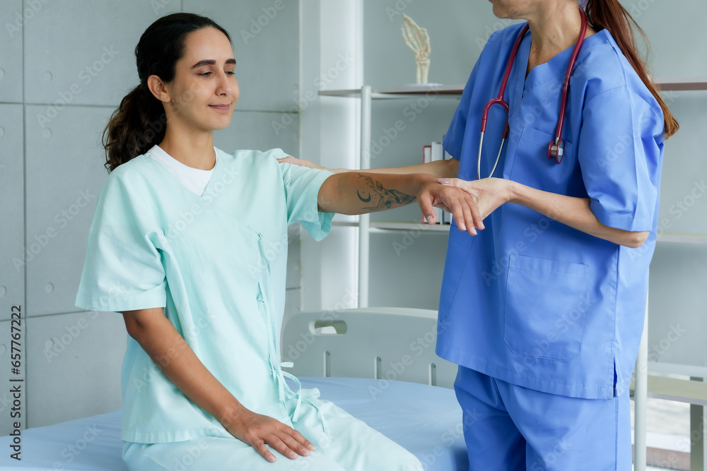 Obraz premium physical therapist anonymous Helping a temporarily paralyzed patient lift his arms back and forth to restore muscle strength. After being unable to move arms on own In hospital examination room