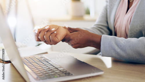 Woman, laptop and hands with wrist pain, injury or carpal tunnel syndrome by office desk. Closeup of female person or employee with sore muscle, ache or joint inflammation from arthritis or strain photo