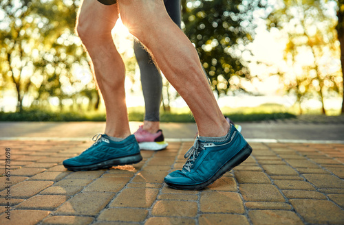 Morning walk on nature. Crop of athletic male person in blue sneakers walking on cobblestone pavement in park together with woman. Active couple leisurely strolling outdoors and breathing fresh air.