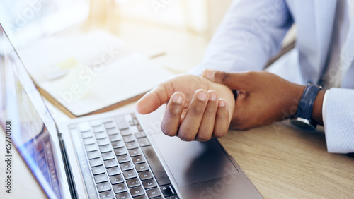 Person, laptop and hands with wrist pain, injury or carpal tunnel syndrome by office desk. Closeup of business employee with sore muscle, ache or joint inflammation from arthritis or strain on table photo