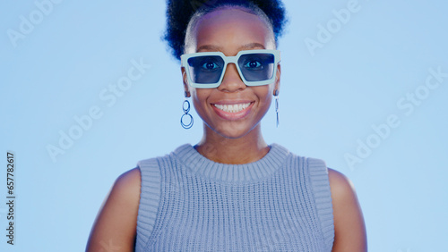 Portrait, sunglasses and smile, black woman in studio with cool, trendy summer fashion and creative mockup. Happiness, luxury eyewear and excited, fun model with designer frame on blue background.