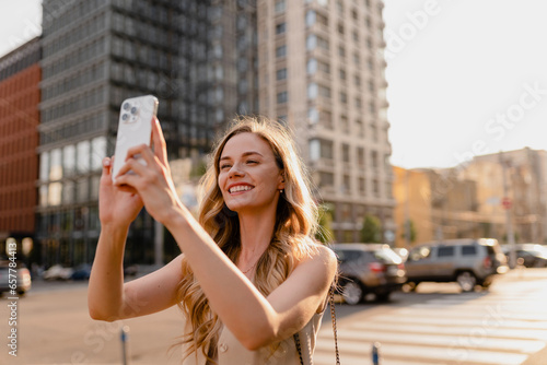 woman walking in sunny city street with phone