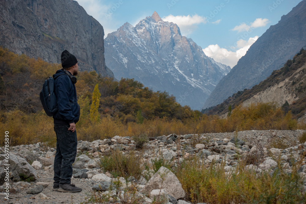 Young man of travelers walking in autumn Kyrgyzstan mountain