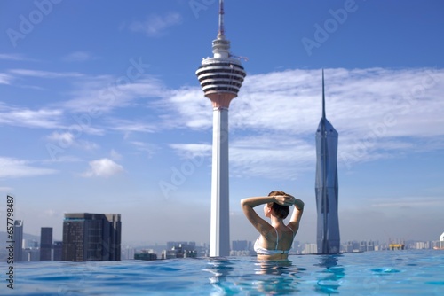 Sticker Portrait of happy young woman in swimming pool on the rooftop of skyscraper hote
