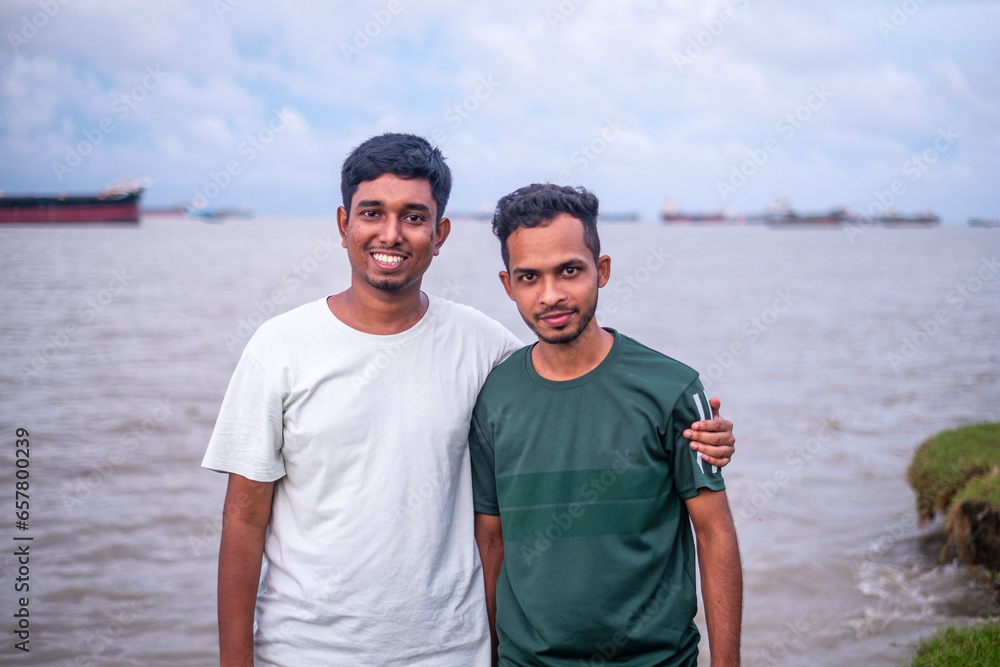 Fototapeta premium Portrait of south asian young boys standing in front of a river wearing casual t shirt