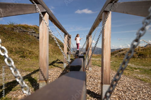 A girl hesitates to step on a movable suspension machine for balance training, Alps, Austria