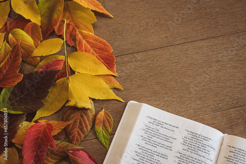 Bible and autumn leaves on a light wood background with copy space