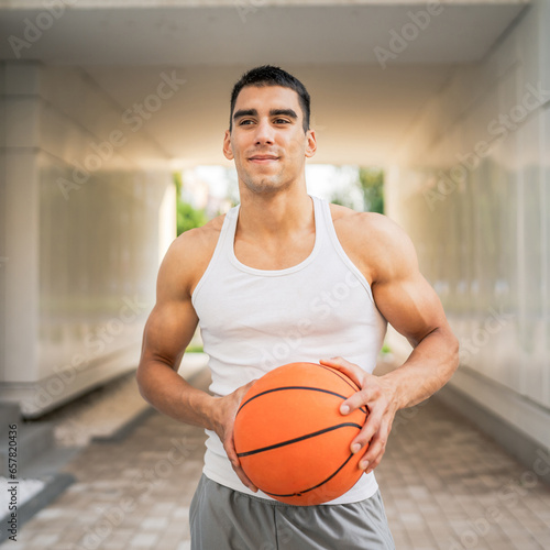 Portrait of strong athlete man hold basketball ball wear white a-shirt