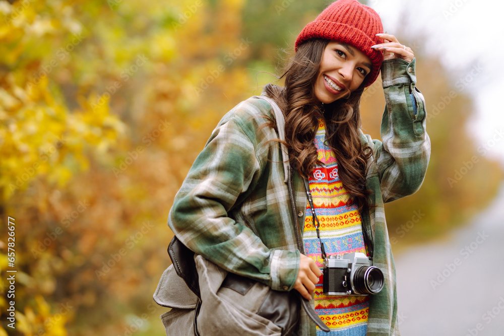 Woman tourist with a retro camera and backpack on a hike in a yellow autumn forest. Young woman walking and having fun outdoors. Woman tourist with a retro camera and backpack on a hike in a yellow autumn forest. Young woman walking and having fun outdoors.