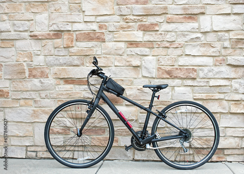 Black Hybrid Bicycle Against Tan Flagstone Wall