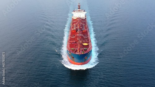 Flying over a crude oil tanker underway in open sea. Bow, forecastle, red upper deck, pipe lines, winches, wheelhouse, upper running bridge, radar mast of a supertanker ship on ride. Aerial, close up
 photo