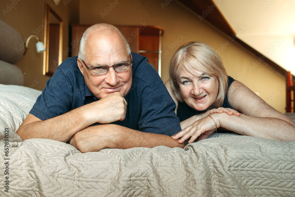 Portrait of a married elderly couple who lies on the bed and looks at the camera Portrait of a married elderly couple who lies on the bed and looks at the camera