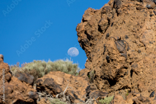 Red rock on Tenerife island, Spain with moon in background and blue sky
