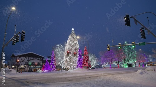Magnificent view of deserted snowy road with traffic lights, Bavarian houses, trees with colorful garlands on a winter night during snowfall, Leavenworth. High quality 4k footage photo