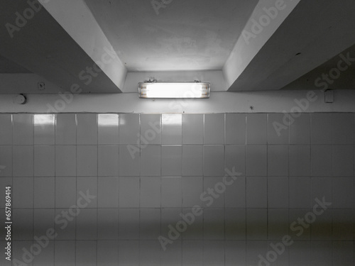 A lamp in a dark underground passage  the walls of which are lined with glossy tiles.