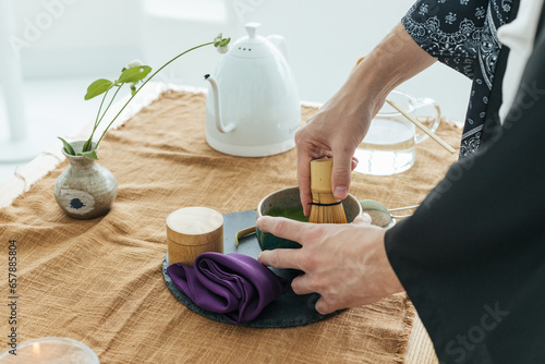 Traditional Japanese green tea match close-up. Matcha tea ceremony, a bamboo Chassen whisk for whipping and tea in a bowl on the brown background.